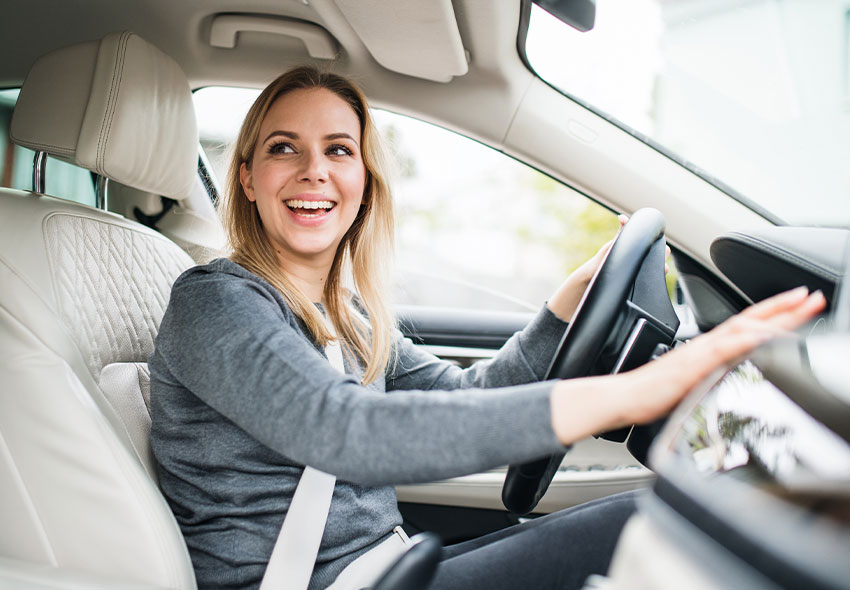 Köp bil Gnosjö En blond glad kvinna som ler inuti en bil